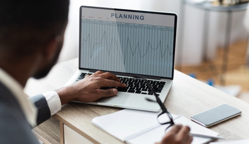 Black businessman working on laptop with annual financial charts on creen, collage